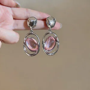 Close-up of elegant silver earrings featuring pink oval stones with chic hollow metal frames