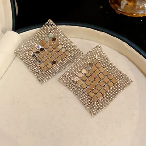 Close-up detail shot of silver geometric sequin fringe earrings displayed in a luxury gift box