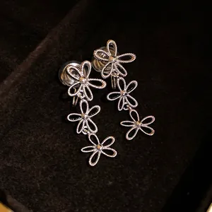Detail view of silver hollow floral tassel clip-on earrings on black velvet