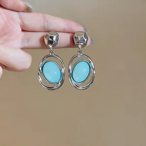 Close-up of luxury silver-tone earrings with smooth light blue oval cabochon stones