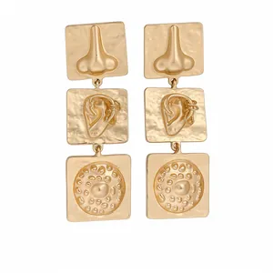 Geometric square drop earrings with abstract gold nose and ear relief sculpture textures