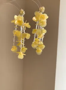 Detailed view of yellow beaded tassel earrings with semi-transparent floral petals
