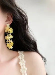 Close-up of model wearing yellow petal tassel earrings with exquisite glass beads