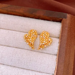 Close-up detail of 18k gold plated heart earrings with sparkling zircon accents.