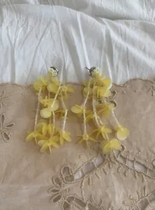 Detailed close-up of handmade yellow glass bead tassel earrings with flower sequins