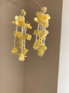 Detail view of yellow petal and glass bead tassel earrings with golden studs
