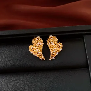 Macro view of elegant 18k gold plated heart stud earrings featuring sparkling white zircons.