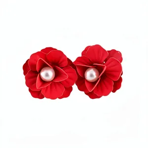 Red floral stud earrings with pearl centers and silver pins for a sweet vacation look.