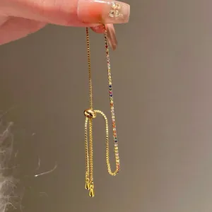 Vue détaillée d'un bracelet en or délicat orné de zircons arc-en-ciel et d'un fermoir coulissant.