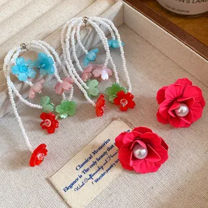Close-up of colorful beaded floral tassel earrings and red pearl flower studs.