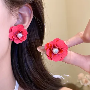 Close-up detail of elegant rose red spray-painted flower earrings with pearl centers on ear