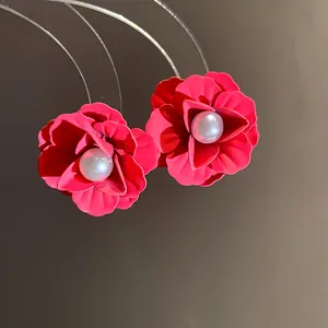 Detail of red flower stud earrings with elegant pearl centers and spray-paint finish