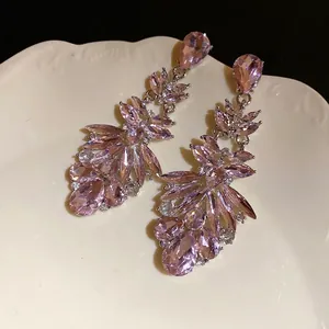 Luxury pink teardrop crystal dangle earrings showcased on a vintage style ceramic plate