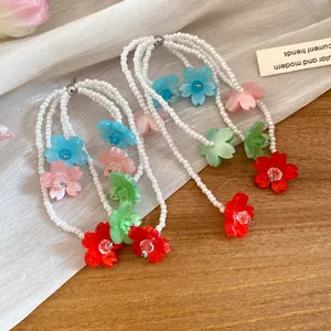 Close-up of colorful spray-painted flower and pearl tassel earrings on white gauze fabric