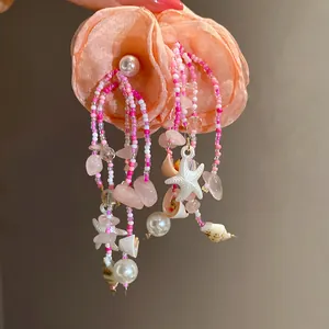 Macro view of vacation style fabric flower earrings with beaded tassels and starfish charms