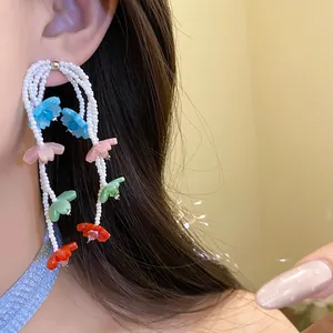 Close-up of vibrant vacation style colorful flower beaded tassel earrings on model