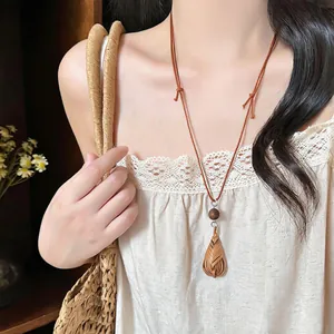 Close-up of a vintage woven water drop pendant on a brown leather cord necklace