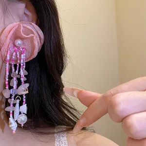 Detailed shot of pink fabric flower tassel earrings with shell and pearl accents