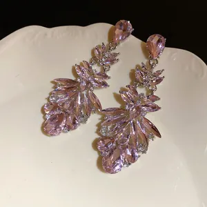 Close-up of elegant pink crystal drop earrings on a white decorative plate.