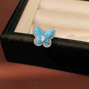 Macro detail of a butterfly ear clip with blue stones and a central marquise zircon