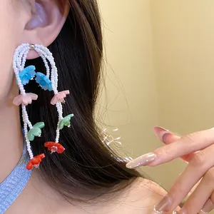 Close-up of colorful beaded flower drop earrings worn by a model in a detail shot.