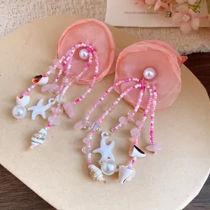 Detailed view of pink fabric flower earrings with shell and starfish tassels.