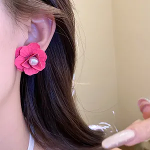 Close-up detail of vibrant pink spray-painted flower stud earring with pearl center