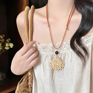 Close-up view of woven rattan sun pendant necklace with leather cord on model