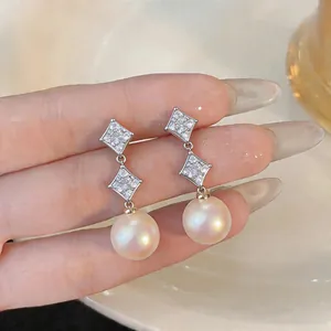 Close-up of elegant drop earrings with starburst zircons and high-luster round pearls