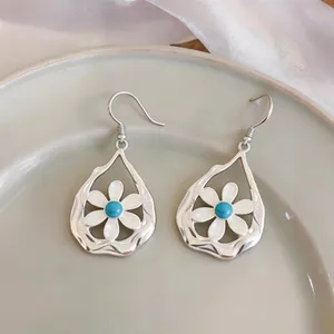 Detailed shot of hollow waterdrop earrings with white flower and blue stone