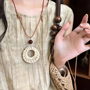 Detailed close-up view of handmade natural rattan woven pendant necklace on brown leather cord