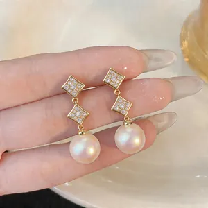 Detail shot of 18K gold plated earrings with sparkling zircon studs and pearl drops