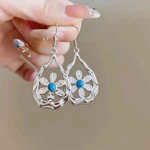 Close-up shot of elegant silver water drop earrings featuring a turquoise flower detail