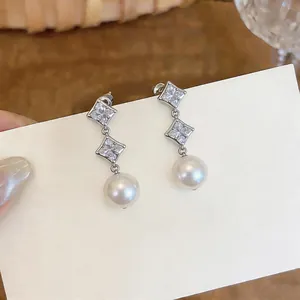 Detail shot of elegant silver drop earrings featuring star-shaped zircons and round pearls.