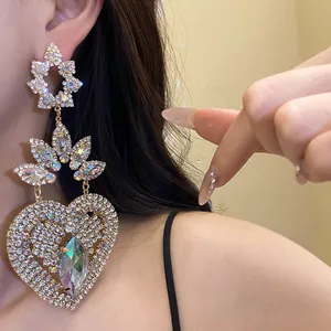 Primer plano de elegantes pendientes largos de corazón con brillantes y diseño floral.