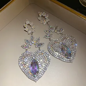 Primer plano de pendientes de corazón grandes con brillantes pedrería y cristales.