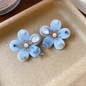 Pendientes elegantes de flores flocadas azul claro con perlas centrales y cristales brillantes