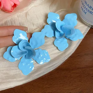 Detailed macro view of light blue enamel flower earrings with glossy layered petals