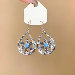 Close-up detail of vintage silver hollow teardrop earrings with central blue flower stone