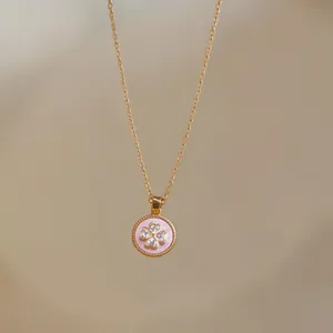 Primo piano di una collana rosa con ciondolo a fiore in zircone placcato oro.