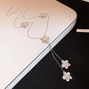 Detalle de collar de metal plateado con colgantes de flores y diseño de borla