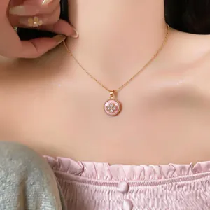 Primo piano di una collana con pendente a fiore rosa e zirconi indossata da una modella