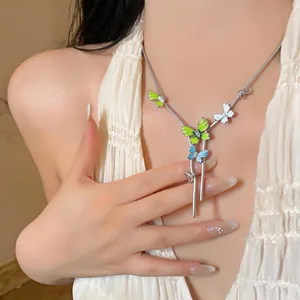 Detail shot of a vibrant enamel butterfly pendant necklace worn by a female model.