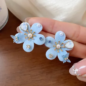 Vista macro detallada de elegantes pendientes de flores flocadas azules con perlas
