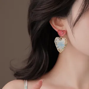 Detailed macro shot of dopamine heart earrings featuring dried flowers and pearls on ear