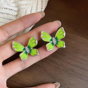 Close-up detail of green enamel butterfly stud earrings with sparkling crystal accents