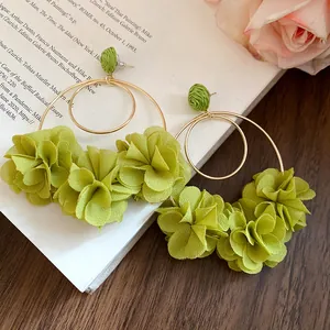 Detail of green chiffon flower and gold hoop earrings with raffia studs.