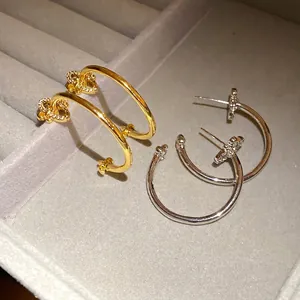 Elegant gold and silver fleur-de-lis C-shaped hoop earrings with zircons