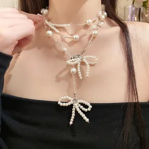 Elegante mehrlagige Perlenkette mit zarten Schleifenanhängern an einem Model.