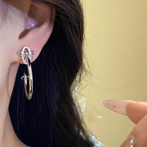 Detailed close-up view of elegant silver fleur-de-lis C-shaped earring on female model